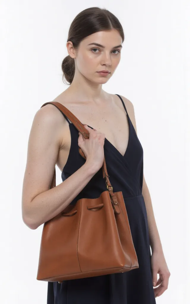 A French female model with a Leather bag, wearing a dress, against a white background, in a front   facing close   up